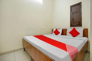 卢迪亚纳Wave Inn Guest House的一张带红色和白色枕头的床