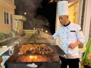 加德满都ROYAL VILLA RESORT的厨师在烧烤架上烹制肉类