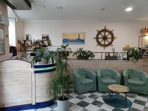 热那亚加拉塔酒店的一间设有绿色椅子和时钟的等候室