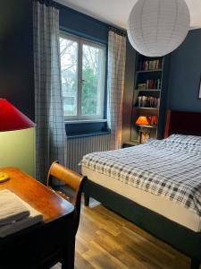 吕贝克The cozy family Retreat Lübeck的一间卧室配有一张床、一张桌子和一个窗户。