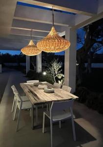 莱乌卡Villa Gabriella的一张带椅子的木桌和两个吊灯