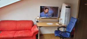 KönizSehr gemütliches und gepflegtes Zimmer 8 Km von Bern-City的客房设有红色的沙发、书桌和电视