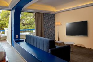 路特奇Ramada Loutraki Poseidon Resort的一间配有沙发和平面电视的酒店客房