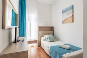 帕格拉海王星旅馆的一间卧室配有一张床和一张书桌及电视