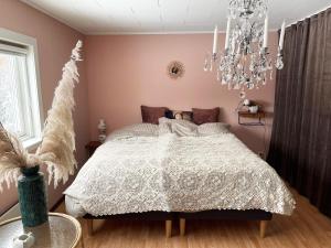 NåsWilderness cabin in Nas near the Vasterdal River的粉红色的卧室配有一张床和吊灯