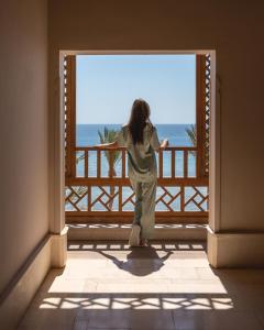 赫尔格达The Makadi Spa Hotel - Couples Only 18 Years Plus的站在一个眺望海洋的阳台上的女人