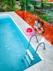 董里Pang Long Chao resort的两个孩子坐在游泳池旁