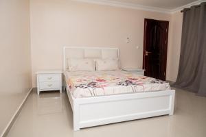 罗安达Casa Chico Rosa的一间白色卧室,配有床和床头柜