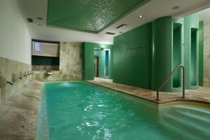 特雷维尼亚诺罗马诺Hotel Recostano Residence的绿色墙壁客房的游泳池