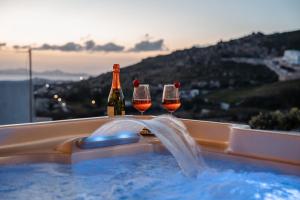 AgkidiaPleiades Villas Naxos2 (Hottub)的热水浴池内的2瓶和2杯葡萄酒