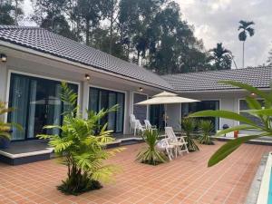 Ban Na KlangPool Villa Nita的房屋设有带椅子和遮阳伞的庭院