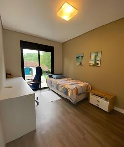 约恩维利Aconchegante Casa 3 suites no Atiradores的一间卧室配有一张床、一张书桌和一个窗户。