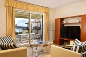 特雷维尼亚诺罗马诺Hotel Recostano Residence的客厅配有电视和桌椅