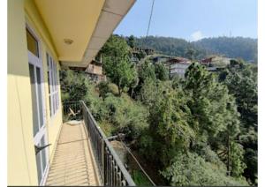 西姆拉Goroomgo Homestay Sukh Dham Shimla - Homestay Like Home Feeling Mountain View的阳台享有树林美景。