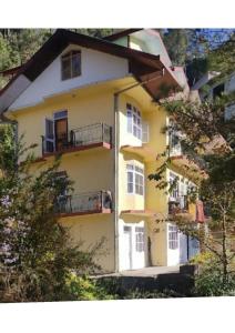 西姆拉Goroomgo Homestay Sukh Dham Shimla - Homestay Like Home Feeling Mountain View的黄色的建筑,旁边设有阳台