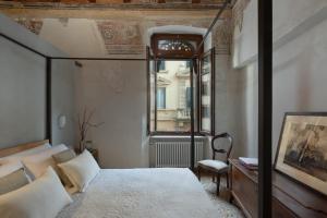 维罗纳罗佳玛姬儿公寓的一间卧室设有四柱床和窗户。