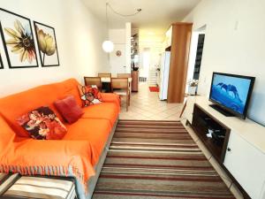 弗洛里亚诺波利斯Apto com sacada e churrasq 100m Praia Brava COI302的客厅配有橙色沙发和平面电视。