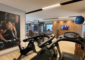 萨尔瓦多嘉年华巴西亚酒店的健身房,配有2台有氧运动器材和一幅女子画