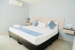 卡塔赫纳Casa Franco Hotel的卧室配有带蓝色枕头的大型白色床