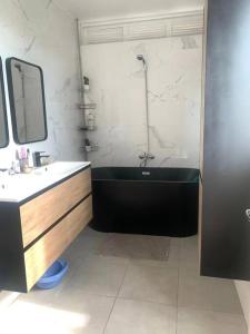 圣克罗蒂德Appartement spacieux的浴室配有黑色浴缸和水槽