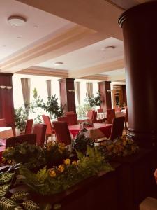 普里什蒂纳HOTEL ORA的用餐室配有红色椅子和鲜花桌