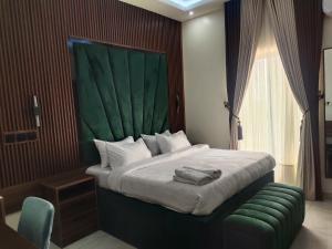 NnewiPassready Hotel and Suites Nnewi的一间卧室配有一张大床和绿色床头板