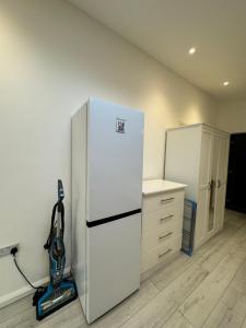 克劳利Studio room next to Gatwick的厨房配有白色冰箱和真空吸尘器