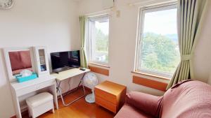 中富良野町拉库琳娜膳食公寓&餐厅的客厅配有书桌、电视和2扇窗户。