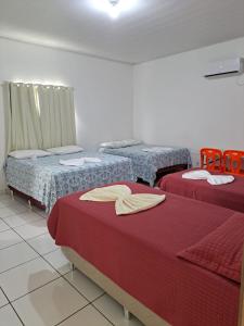 博阿维斯塔Hotel Monte Arau的红色床单的客房内的三张床