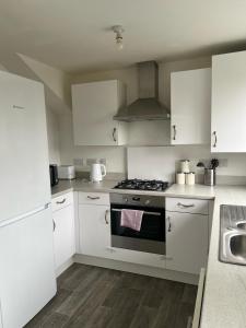 卡迪夫Village House Cardiff - Close to A48 and M4的厨房配有白色橱柜和炉灶烤箱。
