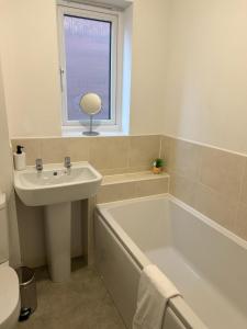 卡迪夫Village House Cardiff - Close to A48 and M4的一间带水槽和浴缸的浴室以及窗户。