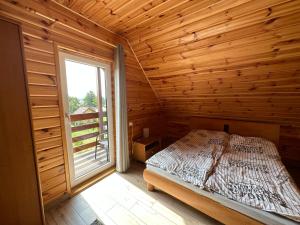 WronyRajska Przystań II的木制客房的一间卧室配有一张床,设有窗户