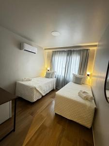 阿拉亚尔-杜卡布Suítes Viver Arraial do Cabo的酒店客房设有两张床和窗户。