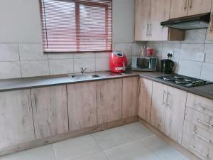 塞昆达Reutlwane Gardens Apartments的一个带水槽和红色用具的厨房