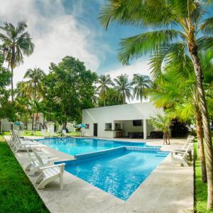 San Luis La Herraduraamaremar的一个带白色椅子和棕榈树的游泳池