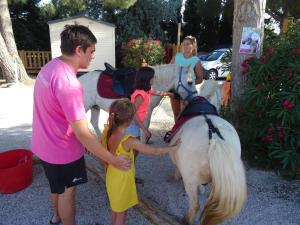 Saint-NazaireCamping Saint-Nazaire的一只男人和两个孩子 ⁇ 着一只白马