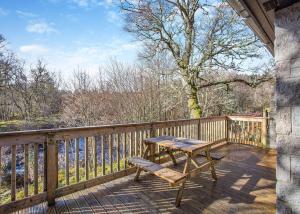WhitebridgeWildside Highland Lodges的木甲板上设有木桌和长凳