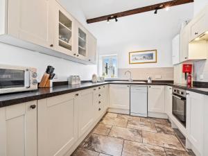 South Barrow达科艾格乡村别墅的厨房配有白色橱柜和瓷砖地板。