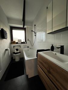 SchönwaldBlack Forest Home的带浴缸、盥洗盆和卫生间的浴室
