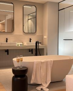 雅典AIONION RESIDENCES by K&K的带浴缸和两杯葡萄酒的浴室