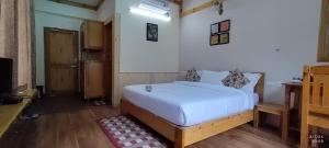 本贾尔Tirthan Grand Riverside的卧室配有白色的床和电视。