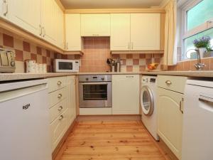 波思利文Sea Star的厨房铺有木地板,配有白色橱柜。