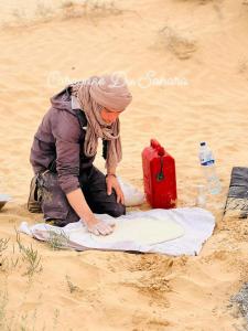 杜兹Private Camp25km-from DOUZ的一位女士用红色手提箱 ⁇ 在沙子里