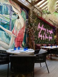 纽约纽约康克尔德酒店的一间带桌椅的餐厅以及一个带壁画的墙壁