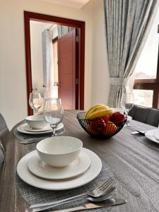 马斯喀特City Gem BAQ的一张桌子,上面放着一碗水果,盘子和玻璃杯