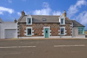 PortknockieCliff Top Cottage with Sea Views的街上有一扇蓝色门的砖房