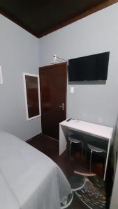 布卢梅瑙Pousada Casa da Maga - Centro的一间卧室配有一张床、一张书桌和一台电视。