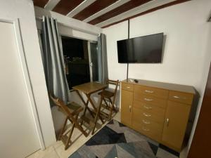 新伊瓜苏Suite 3, Casa Amarela, Terceiro Andar的配有电视和带桌椅的梳妆台的客房