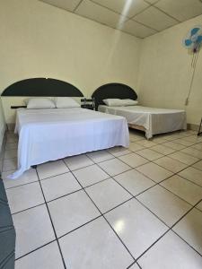 圣安娜Casa 25 hostal的一间带两张床的卧室,铺有瓷砖地板。