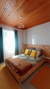 马希库Kanela Guest house的一间卧室设有一张带木制天花板的大床